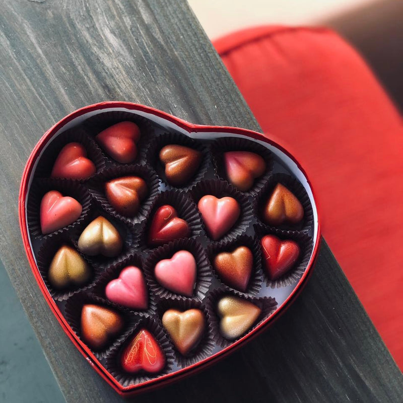 Red heart shaped box filled with handpainted and filled chocolate hearts, strawberry and white chocolate ganache
